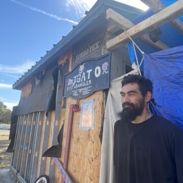 A homeless man stands outside a shack he built to live in at a park in San Jose, California