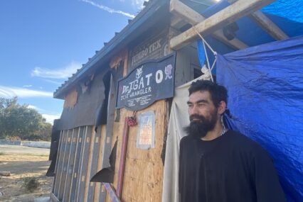 A homeless man stands outside a shack he built to live in at a park in San Jose, California