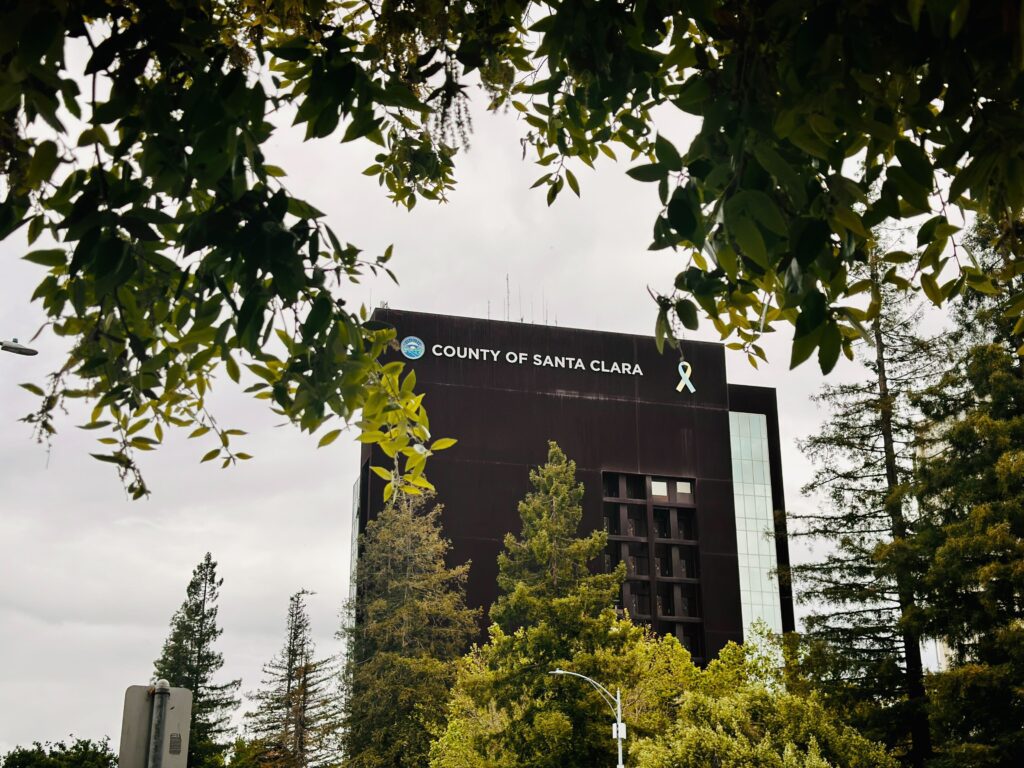 The exterior of the Santa Clara County Government Center framed by tree branches