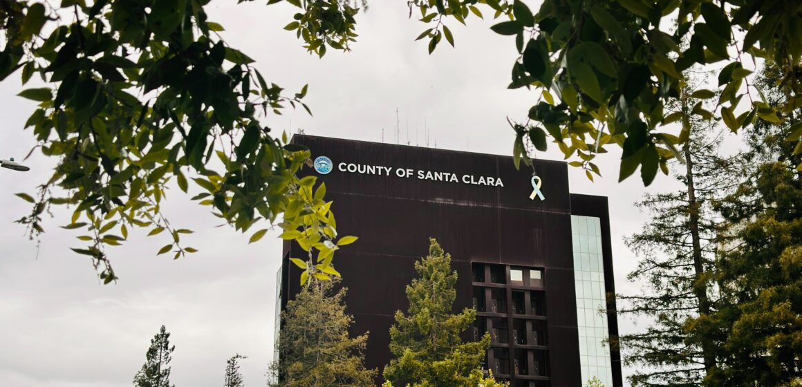 The exterior of the Santa Clara County Government Center framed by tree branches