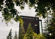 The exterior of the Santa Clara County Government Center framed by tree branches
