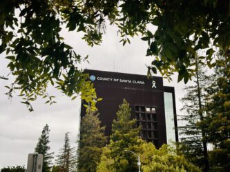 The exterior of the Santa Clara County Government Center framed by tree branches