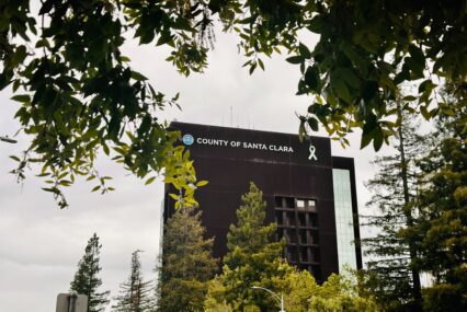 The exterior of the Santa Clara County Government Center framed by tree branches