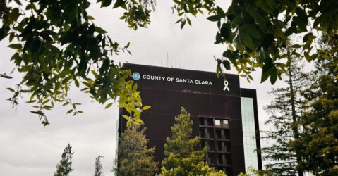 The exterior of the Santa Clara County Government Center framed by tree branches