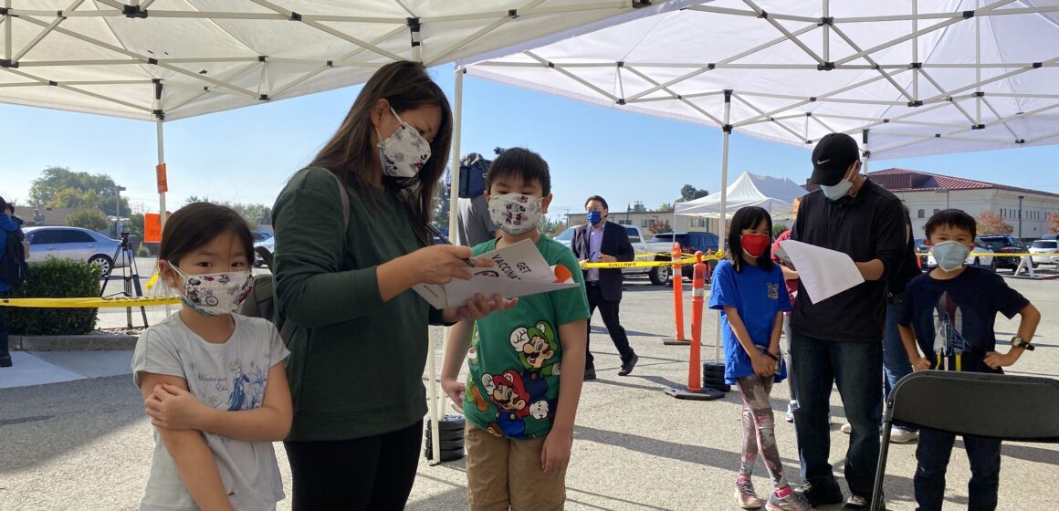 Two children and their mother standing in line to get COVID vaccinations in San Jose, California