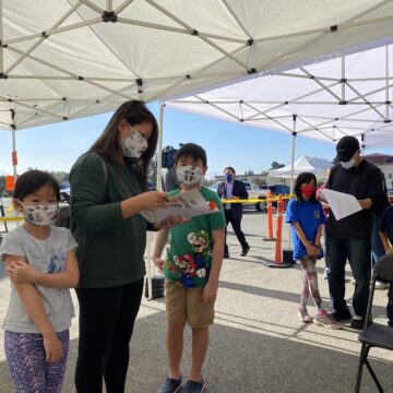 Two children and their mother standing in line to get COVID vaccinations in San Jose, California