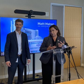 Susana Alcala Wood A man and woman stand at a podium