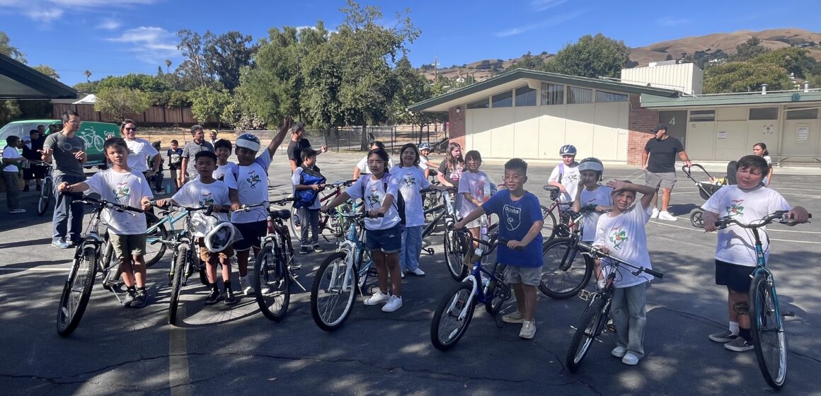 BIKE DONATIONS Elementary school students sit on bikes in a parking lot
