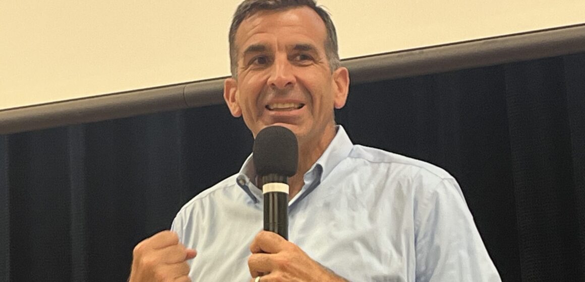 A man in a dress shirt speaks into a microphone