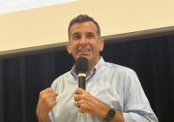 A man in a dress shirt speaks into a microphone