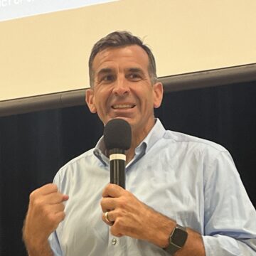 A man in a dress shirt speaks into a microphone