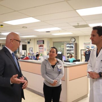 A man in a suit speaks to a female lead nurse and a male doctor in a hospital in San Jose, California