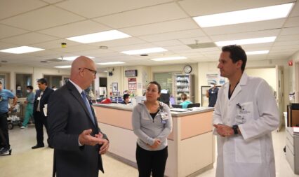 A man in a suit speaks to a female lead nurse and a male doctor in a hospital in San Jose, California
