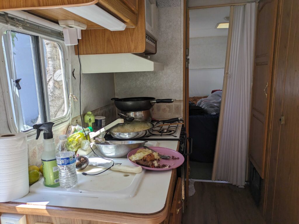 The inside of a small kitchen in an RV, with pots and pans on the counter