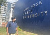 A student stands in front of a sign at San Jose State University
