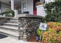 A sign sticks out of the ground in a resident's front yard that reads, "Warning! Protected by Surveillance Solutions alarm system."