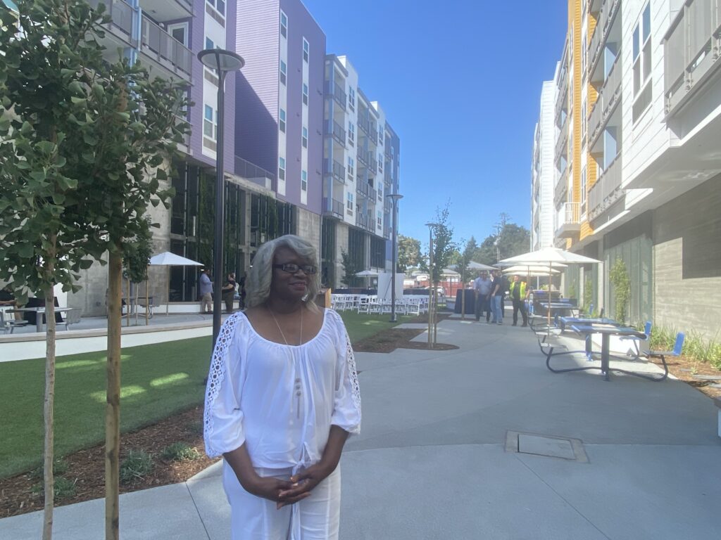 A woman standing outside in a courtyard between two apartment buildings
