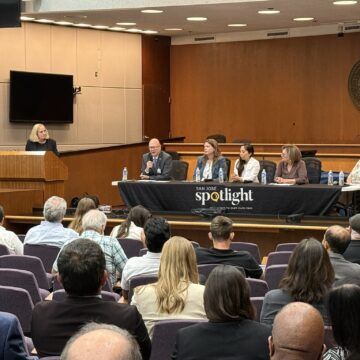 A seated audience looking at a panel of people behind a table