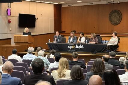 A seated audience looking at a panel of people behind a table