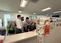 A group of people in a cubicle looking at a computer