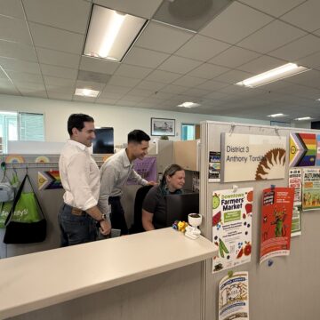 A group of people in a cubicle looking at a computer