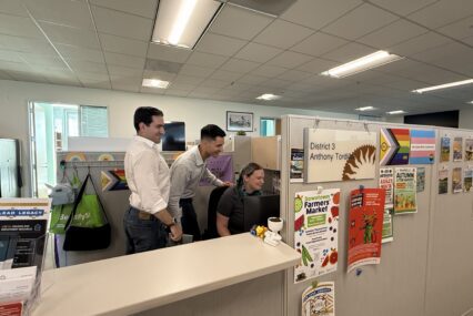 A group of people in a cubicle looking at a computer