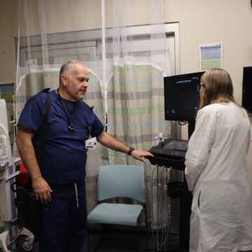 A man in scrubs speaks to a woman in a doctor's coat at a hospital in East San Jose, California