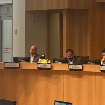 Four people sitting behind the dais at a government meeting in San Jose, California