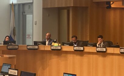 Cuatro personas sentadas detrás del estrado en una reunión gubernamental en San José, California.