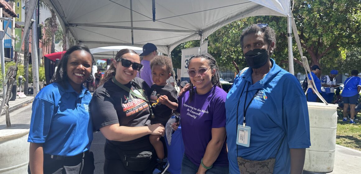 Bốn người phụ nữ da màu đứng bên ngoài, một người bế một đứa trẻ mới biết đi