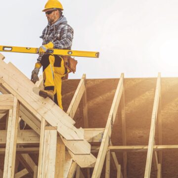 A construction worker on top of a house being built
