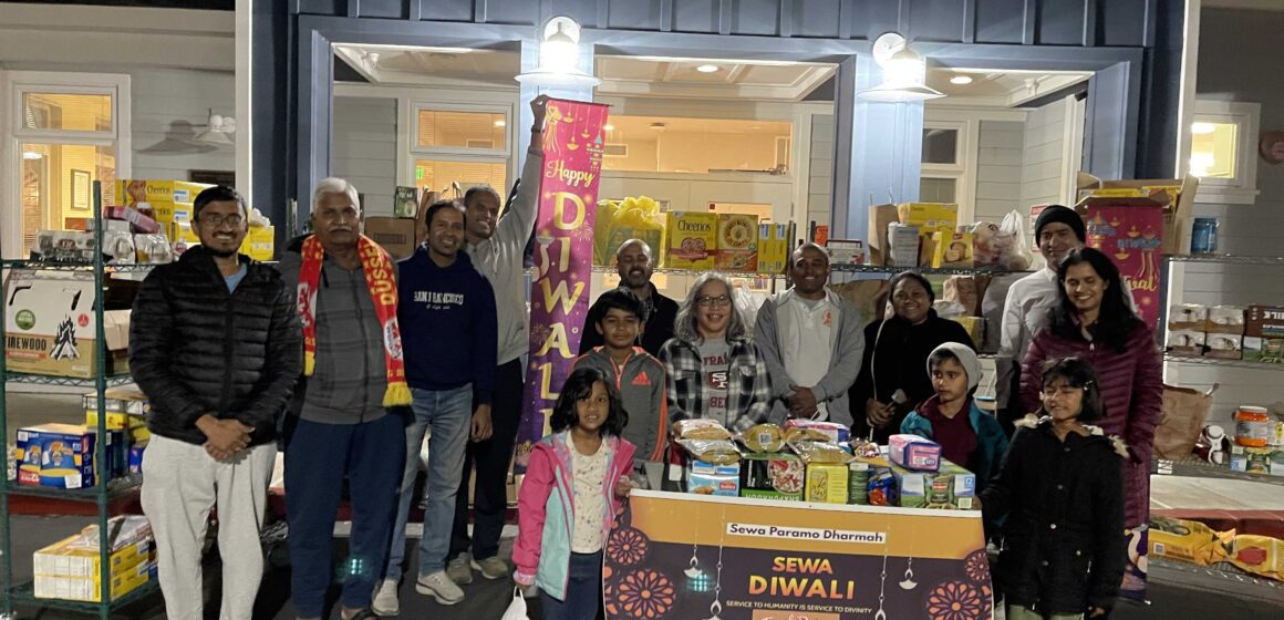 A group of children and adults stand in front of West Valley Community Services surrounded by groceries
