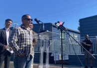 A man stands outside speaking into a microphone at a podium in San Jose, California