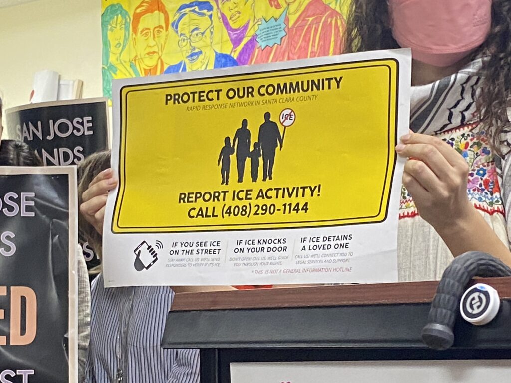 A woman holds up a sign during a news conference.