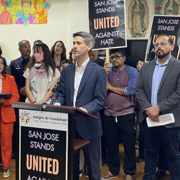 A man in a suit stands at a podium in front of a group of people.