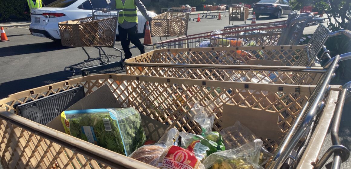 Cathedral of Faith food distribution A man in a yellow safety vest pulls shopping carts through a parking lot.