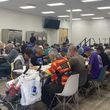 People sitting at tables eating a meal provided by a food aid nonprofit