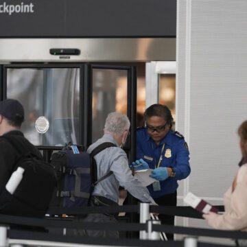 TSA People go through a TSA checkpoint at an airport