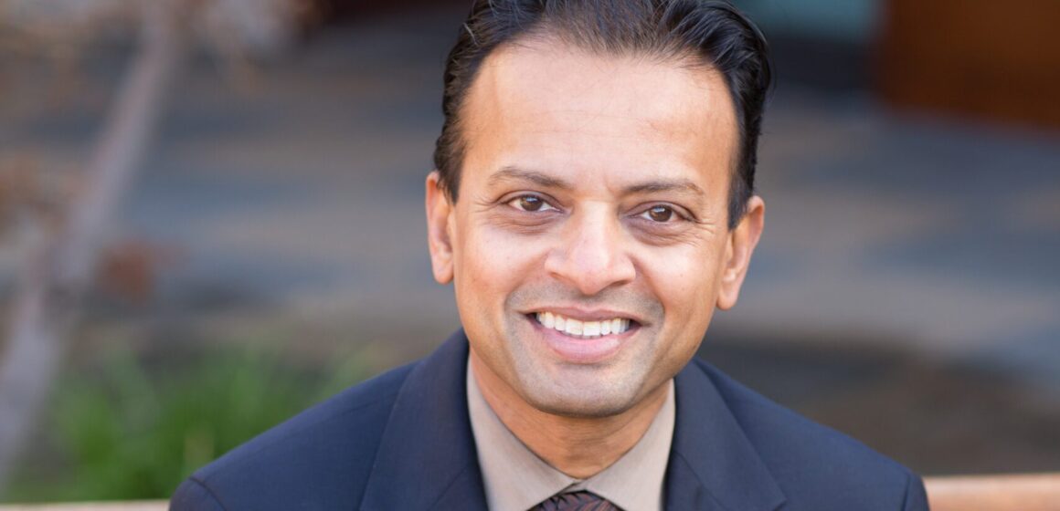 A man in a suit with an American flag pin sitting on a bench