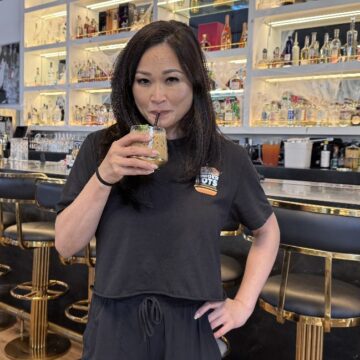 Breaking Dawn Brunch A woman sips a drink from a straw in a restaurant, with a bar behind her
