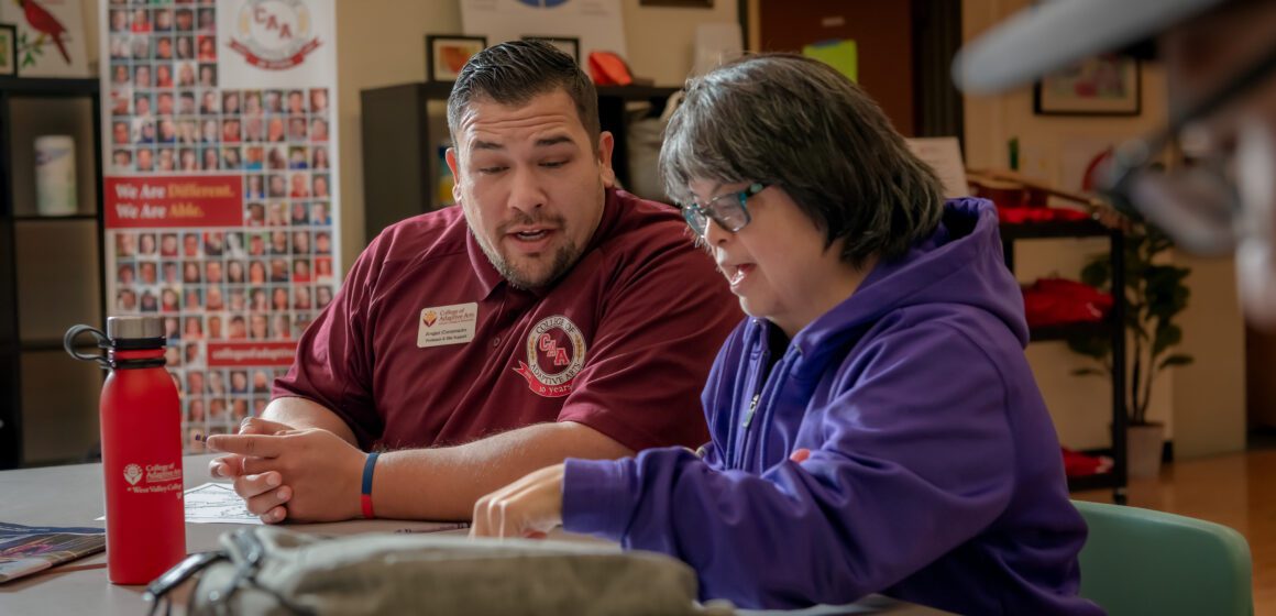 A professor sits with a student at a college in Saratoga, California.
