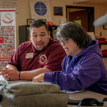 A professor sits with a student at a college in Saratoga, California.