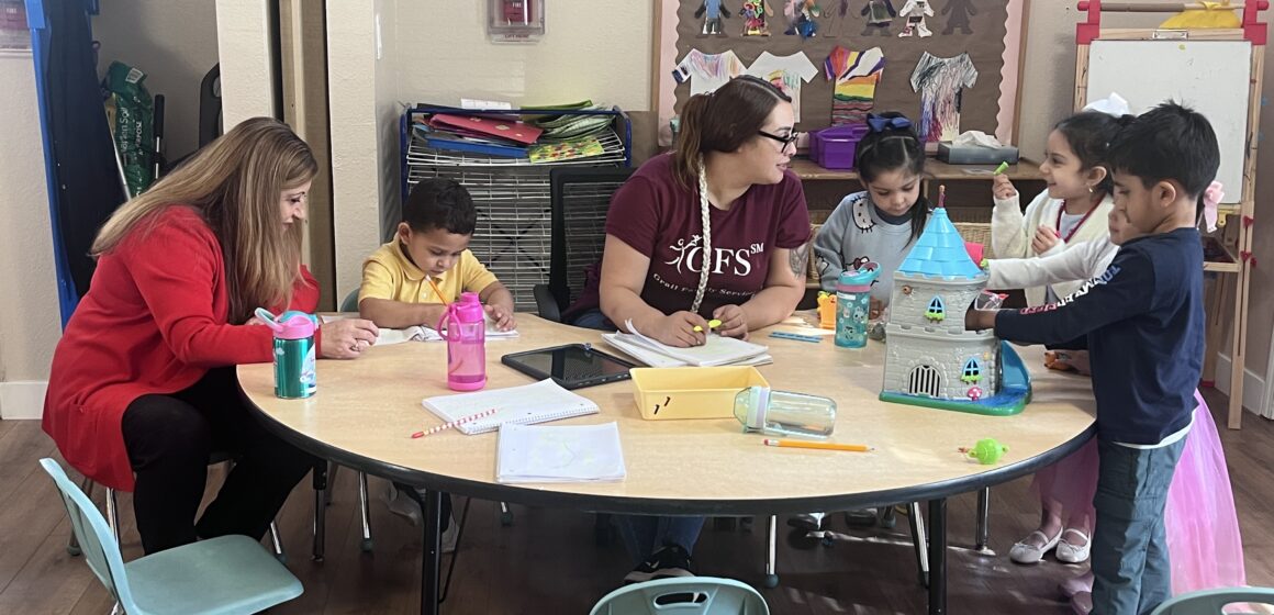 Mujeres y niños sentados y jugando en una mesa