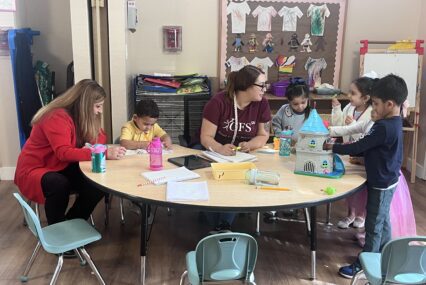 Women and children sitting and playing at a table