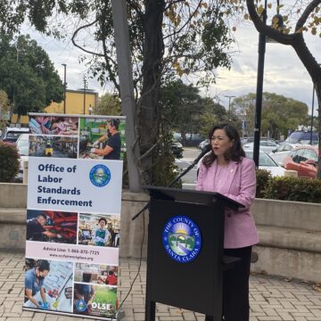 A woman speaks outside at a podium
