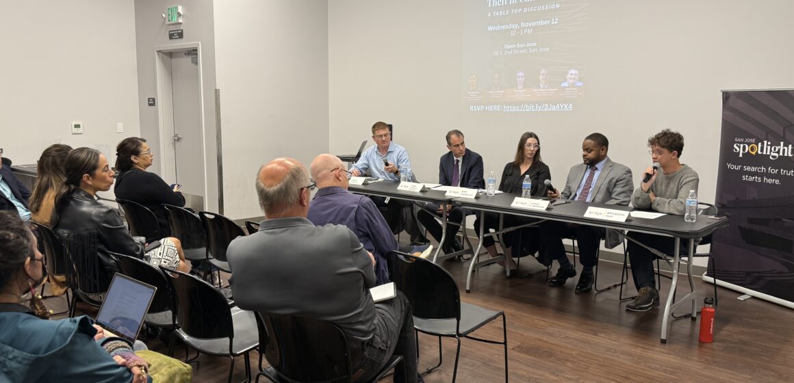 An audience watches a panel of people talking at a table