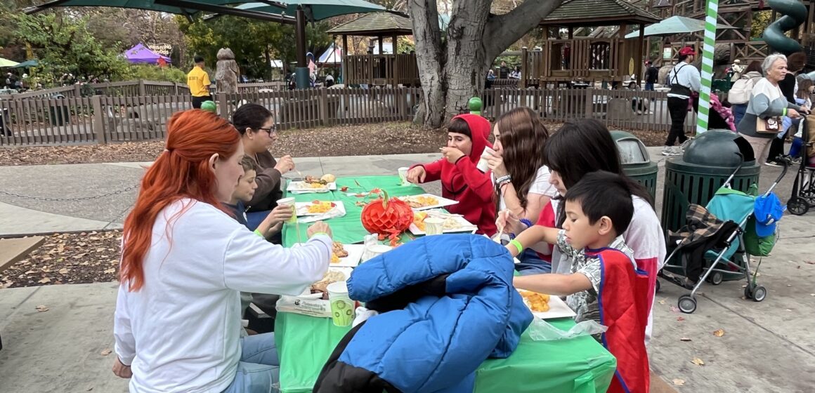 Children and their families sitting at a table at Happy Hollow in San Jose, California