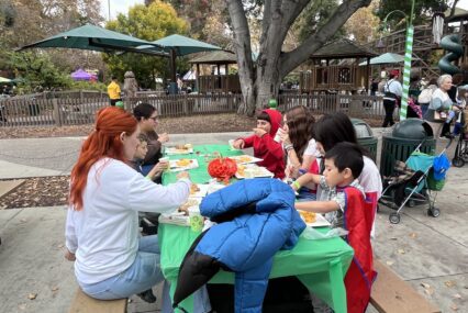 Children and their families sitting at a table at Happy Hollow in San Jose, California