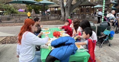 Children and their families sitting at a table at Happy Hollow in San Jose, California