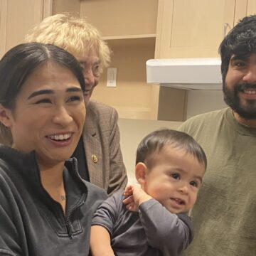 Continuum of Care Grants--Kaytanna Alvarido and Alberto Barragan San Jose A woman holding a young child stands next to a man in a kitchen